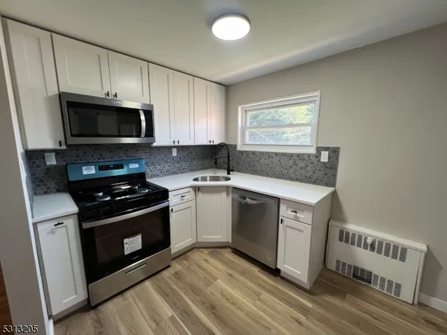 a kitchen with granite countertop a stove a microwave a sink and cabinets