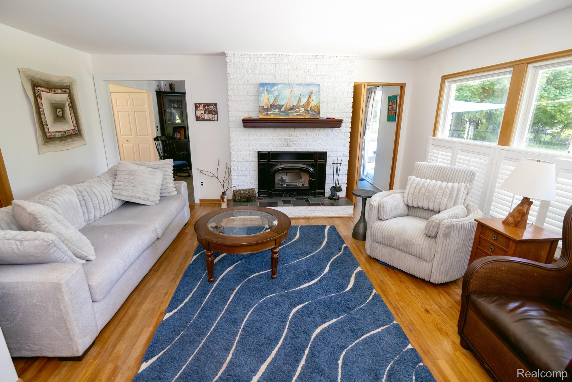 724 Sandstone Drive Rochester, MI 48309 - Photo 23 of 60 Living area featuring hardwood flooring, a white brick fireplace with a wood mantle, and a built-in wood-burning insert
