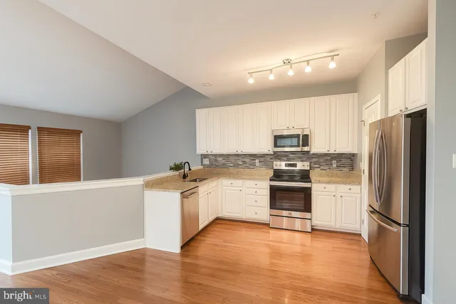 a kitchen with granite countertop a refrigerator and a stove top oven