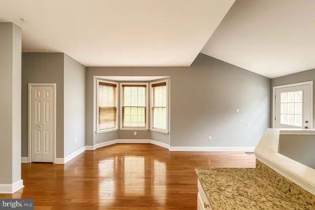 a view of an empty room with window and wooden floor
