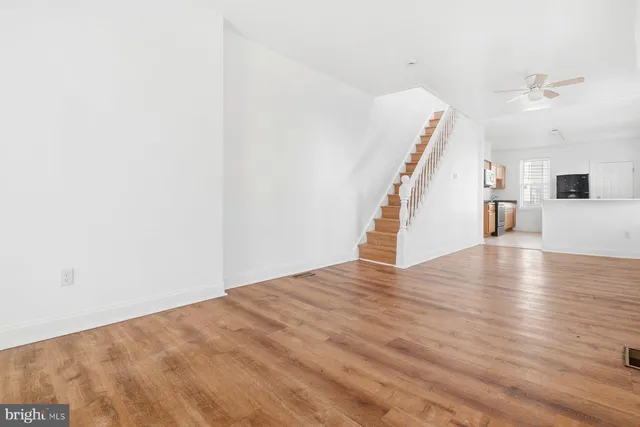 a view of an empty room with wooden floor and stairs