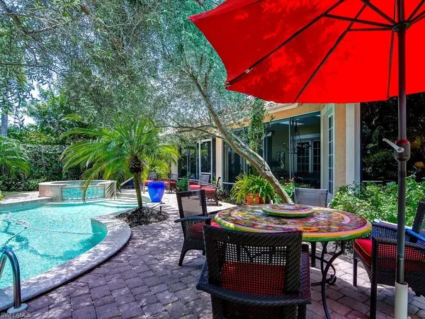 a view of a table and chairs under an umbrella in backyard
