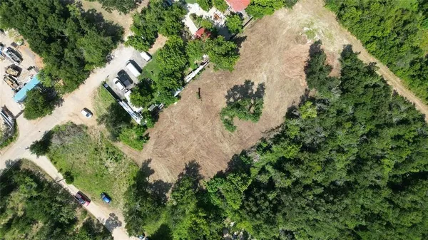 an aerial view of a house with a yard and covered with trees