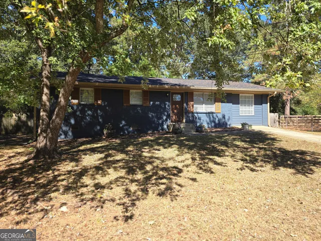a backyard of a house with table and chairs under an umbrella