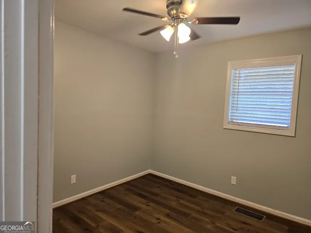 an empty room with wooden floor closet fan and windows