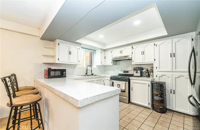 a kitchen with a stove a refrigerator and white cabinets