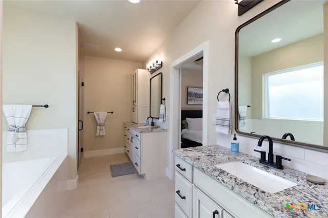 a spacious bathroom with a tub sink and mirror