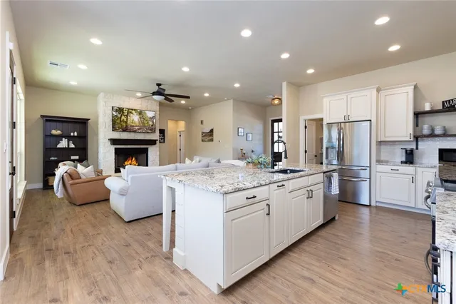 a open kitchen with granite countertop a stove top oven a sink dishwasher and a fireplace with wooden floor