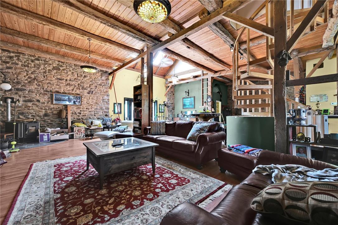 101 Conrad Road Fleetwood, PA 19522 - Photo 4 of 42 A spacious living area with warm wood ceilings and stone walls, featuring a unique spiral staircase and inviting fireplace.