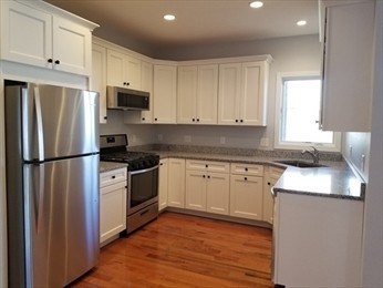 43 Harvard Street, Unit 1 Winchester, MA 01890 - Photo 2 of 13 a kitchen with stainless steel appliances granite countertop a refrigerator sink and cabinets