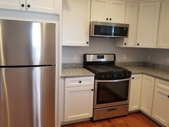43 Harvard Street, Unit 1 Winchester, MA 01890 - Photo 3 of 13 a kitchen with stainless steel appliances granite countertop white cabinets and wooden floor