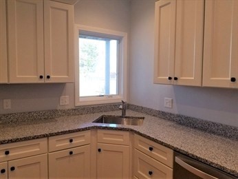 43 Harvard Street, Unit 1 Winchester, MA 01890 - Photo 4 of 13 a kitchen with granite countertop white cabinets and sink