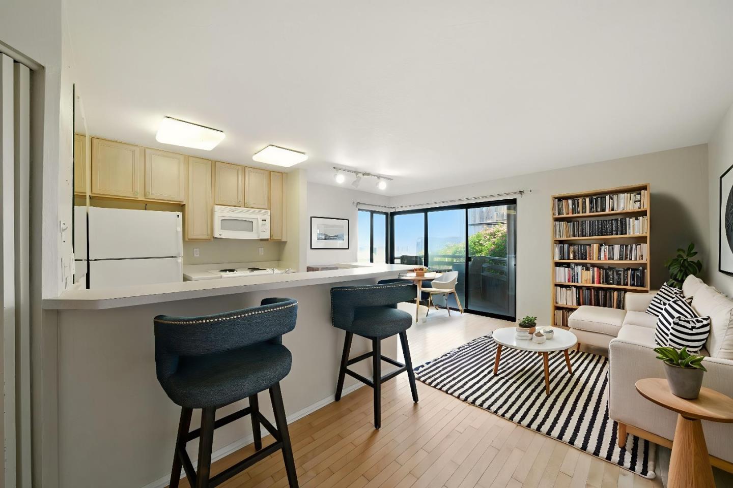125 Surf Way, Unit 343 Monterey, CA 93940 - Photo 2 of 8 a kitchen with a table chairs refrigerator and cabinets