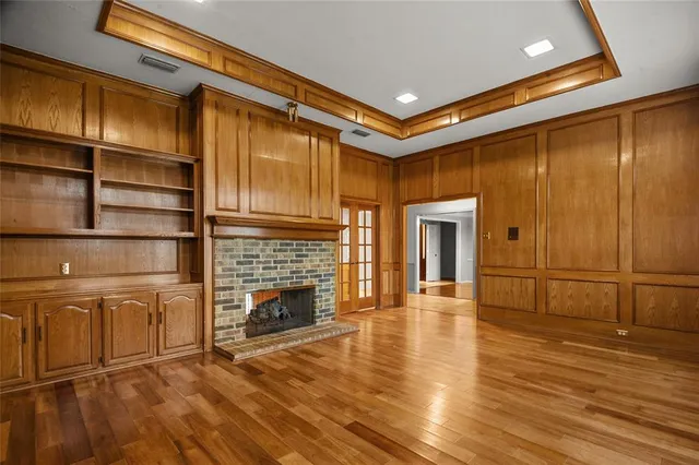 a view of an empty room with wooden floor and a fireplace