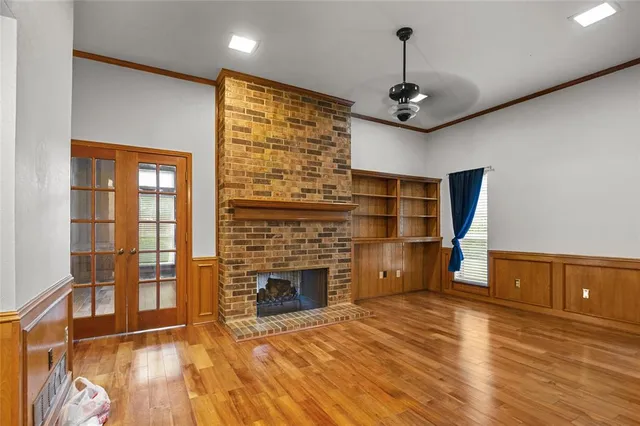 a view of a livingroom with wooden floor a ceiling fan and windows
