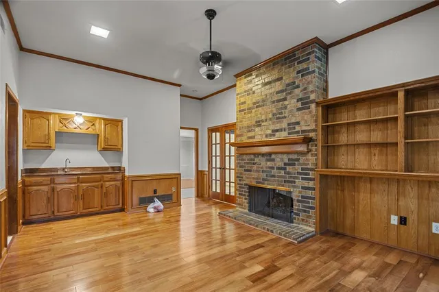 a living room with stainless steel appliances granite countertop a fireplace cabinets and a wooden floor