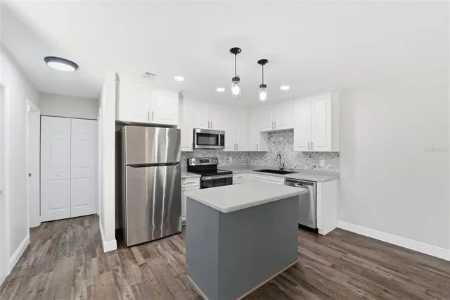 a kitchen with kitchen island a sink stainless steel appliances and cabinets