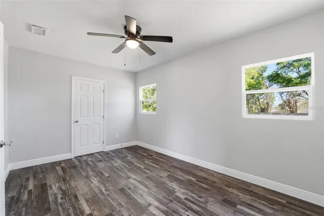 a view of empty room with wooden floor and fan