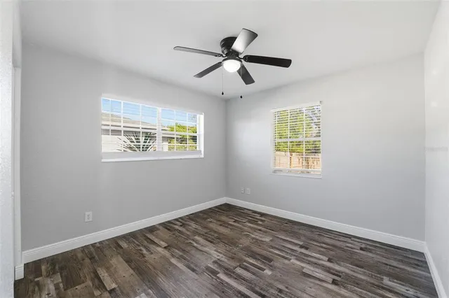 a view of empty room with wooden floor and fan