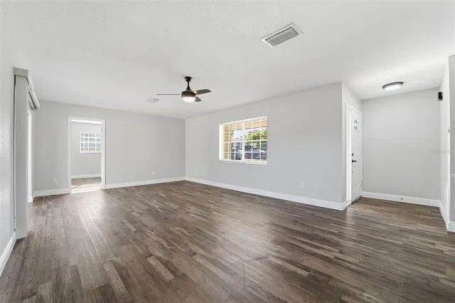 an empty room with wooden floor chandelier and windows
