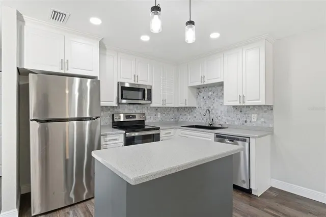 a kitchen with a refrigerator a microwave a sink and cabinets