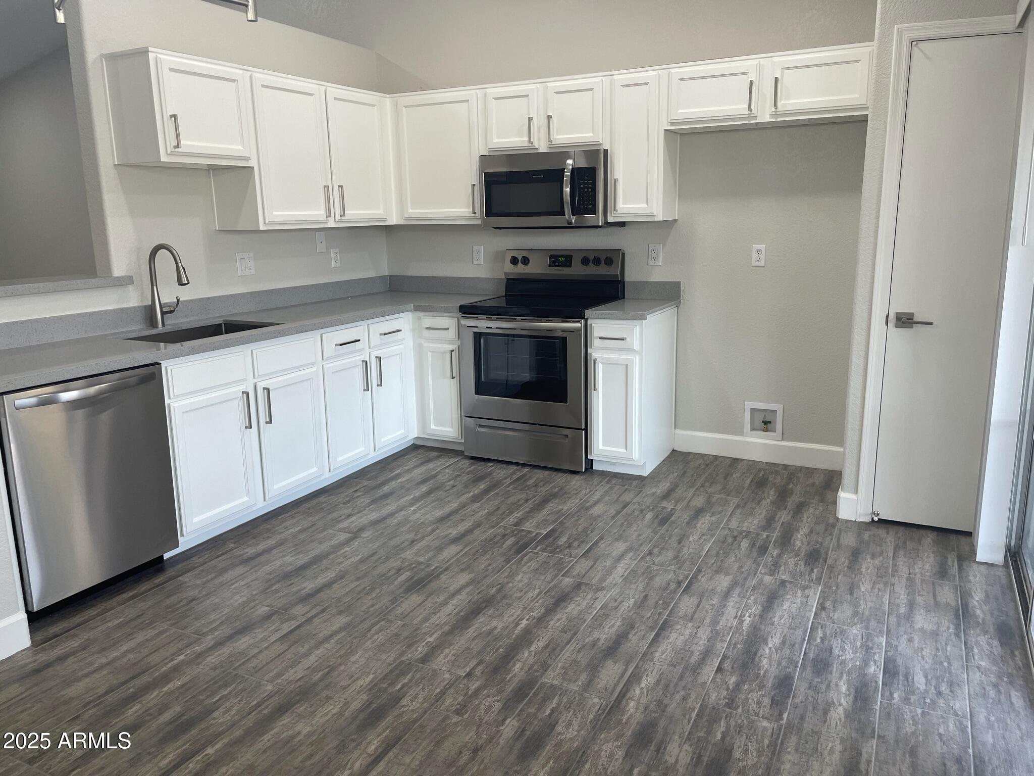 839 West 12th Avenue Apache Junction, AZ 85120 - Photo 5 of 26 a kitchen with stainless steel appliances a stove top oven a sink and white cabinets