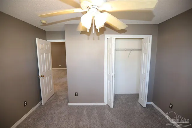 an empty room with a chandelier fan and closet