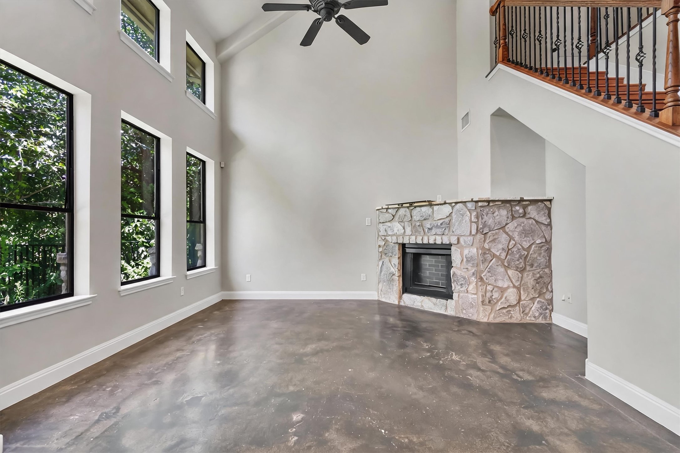 1010 Immanuel Road, Unit 103 Pflugerville, TX 78660 - Photo 6 of 30 A spacious living room features soaring ceilings, a corner stone fireplace, and abundant natural light from tall windows.