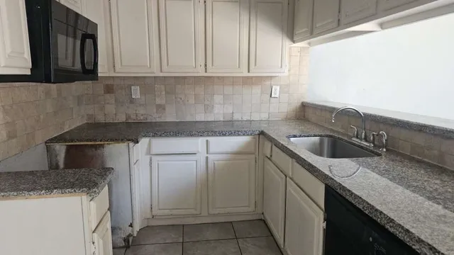 a kitchen with granite countertop a sink stove and cabinets