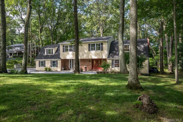 a view of a house with a big yard and large trees