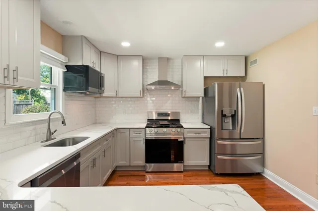 a kitchen with stainless steel appliances granite countertop a stove a refrigerator and a sink