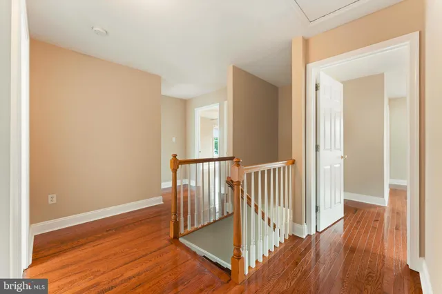 a view of a hallway with wooden floor and a bathroom