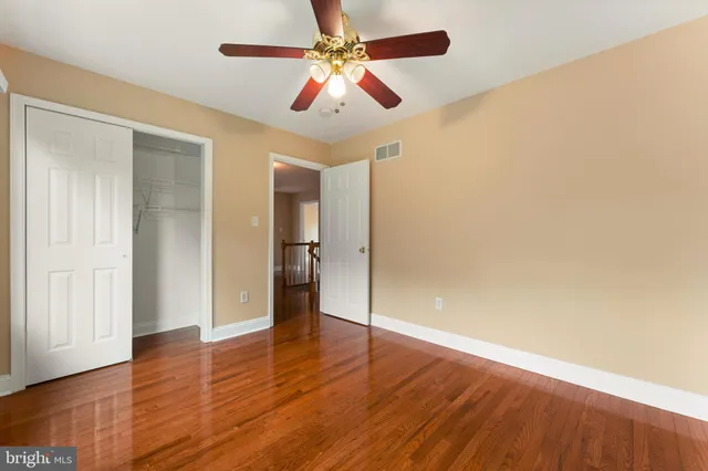 an empty room with wooden floor chandelier fan and windows