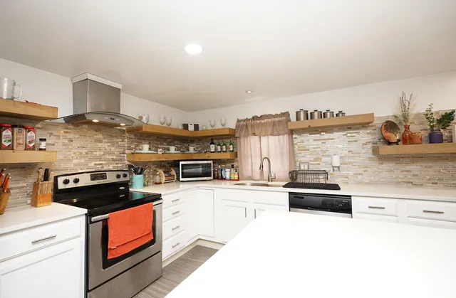 a kitchen with stainless steel appliances kitchen island granite countertop a stove and a sink