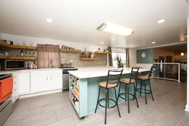 a kitchen with stainless steel appliances kitchen island granite countertop a stove and a refrigerator