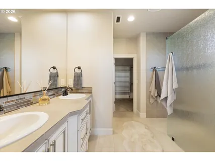 a bathroom with a double vanity sink a mirror and a shower