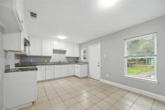 a kitchen with granite countertop white cabinets and white appliances