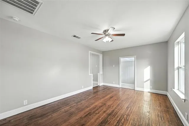 a view of an empty room with a window and wooden floor