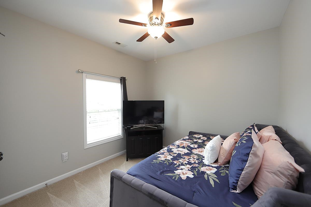 1105 Weston Green Loop Cary, NC 27513 - Photo 19 of 24 a bed sitting in a bedroom next to a window with a chandelier