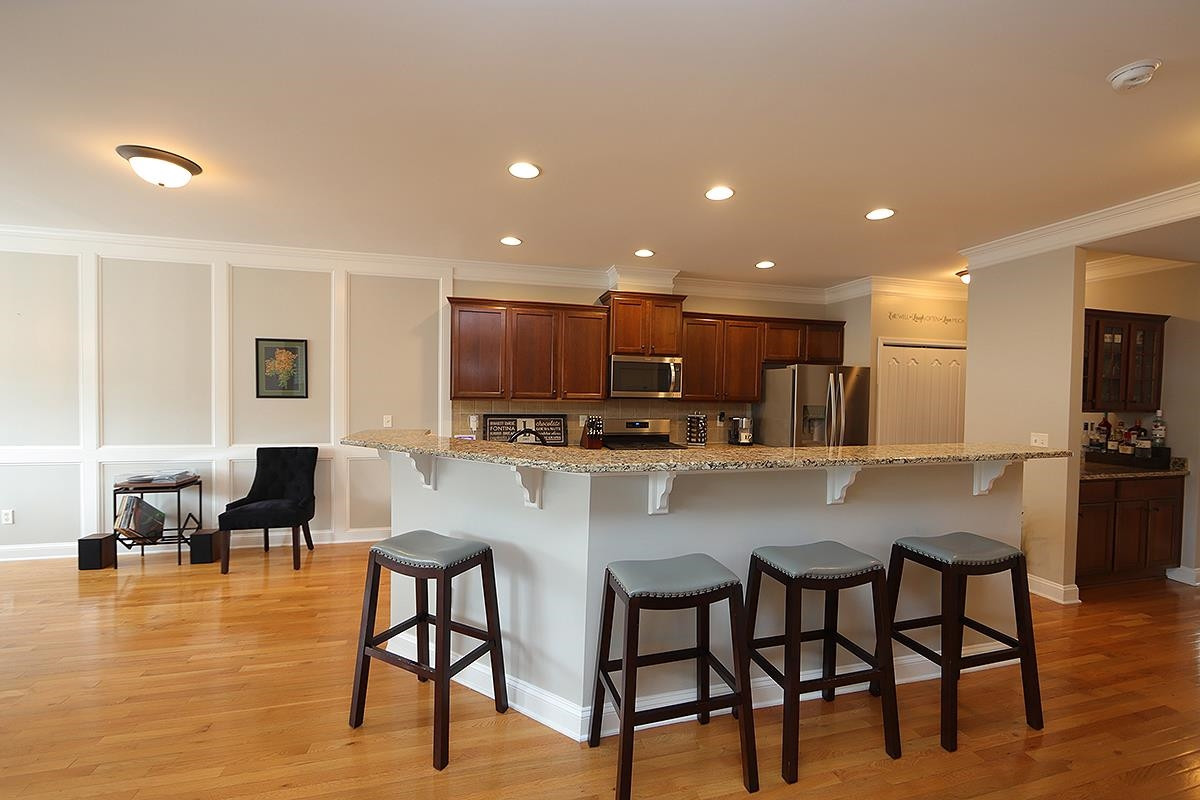 1105 Weston Green Loop Cary, NC 27513 - Photo 6 of 24 a kitchen with stainless steel appliances kitchen island granite countertop a dining table chairs and a refrigerator a sink with wooden floor