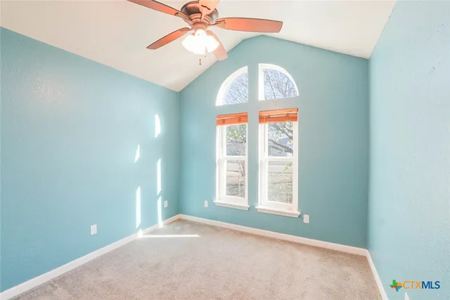 an empty room with windows and a chandelier fan