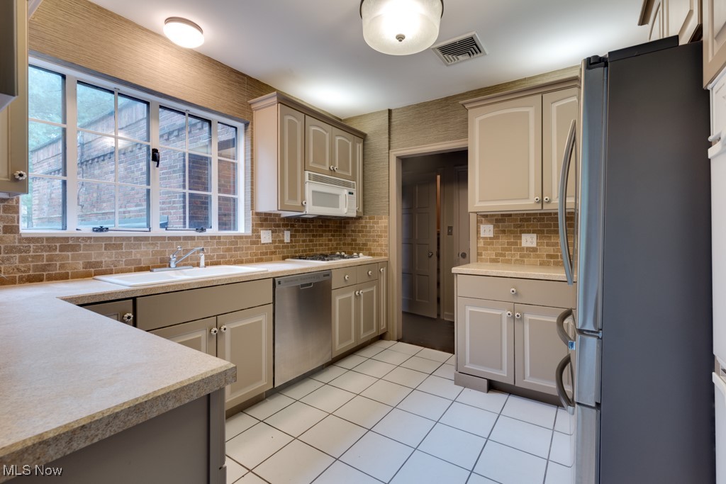 569 Merriman Road Akron, OH 44303 - Photo 20 of 43 Kitchen featuring light tile patterned floors, appliances with stainless steel finishes, sink, and decorative backsplash