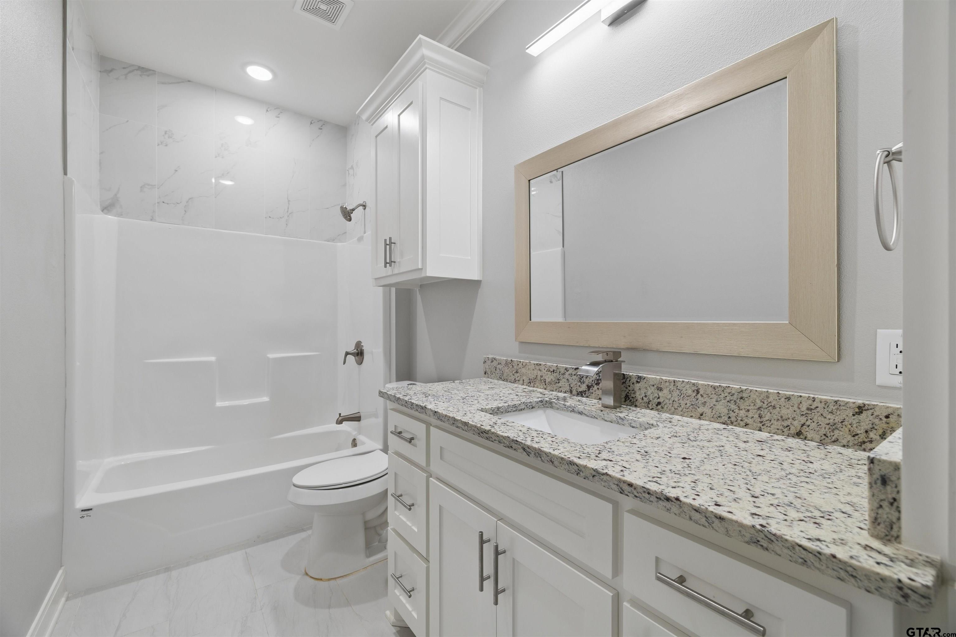 629 Third Street Bullard, TX 75757 - Photo 11 of 18 a bathroom with a granite countertop sink a toilet and a large mirror