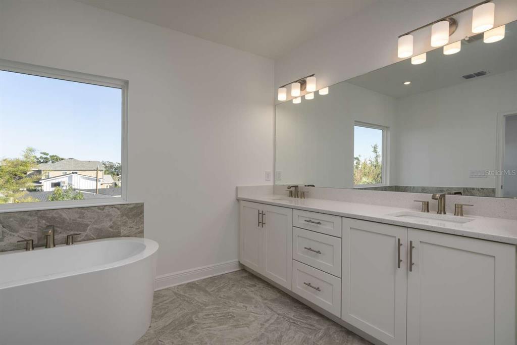 318 Rafael Boulevard Northeast St. Petersburg, FL 33704 - Photo 22 of 38 a spacious bathroom with a double vanity sink a large mirror and a bathtub