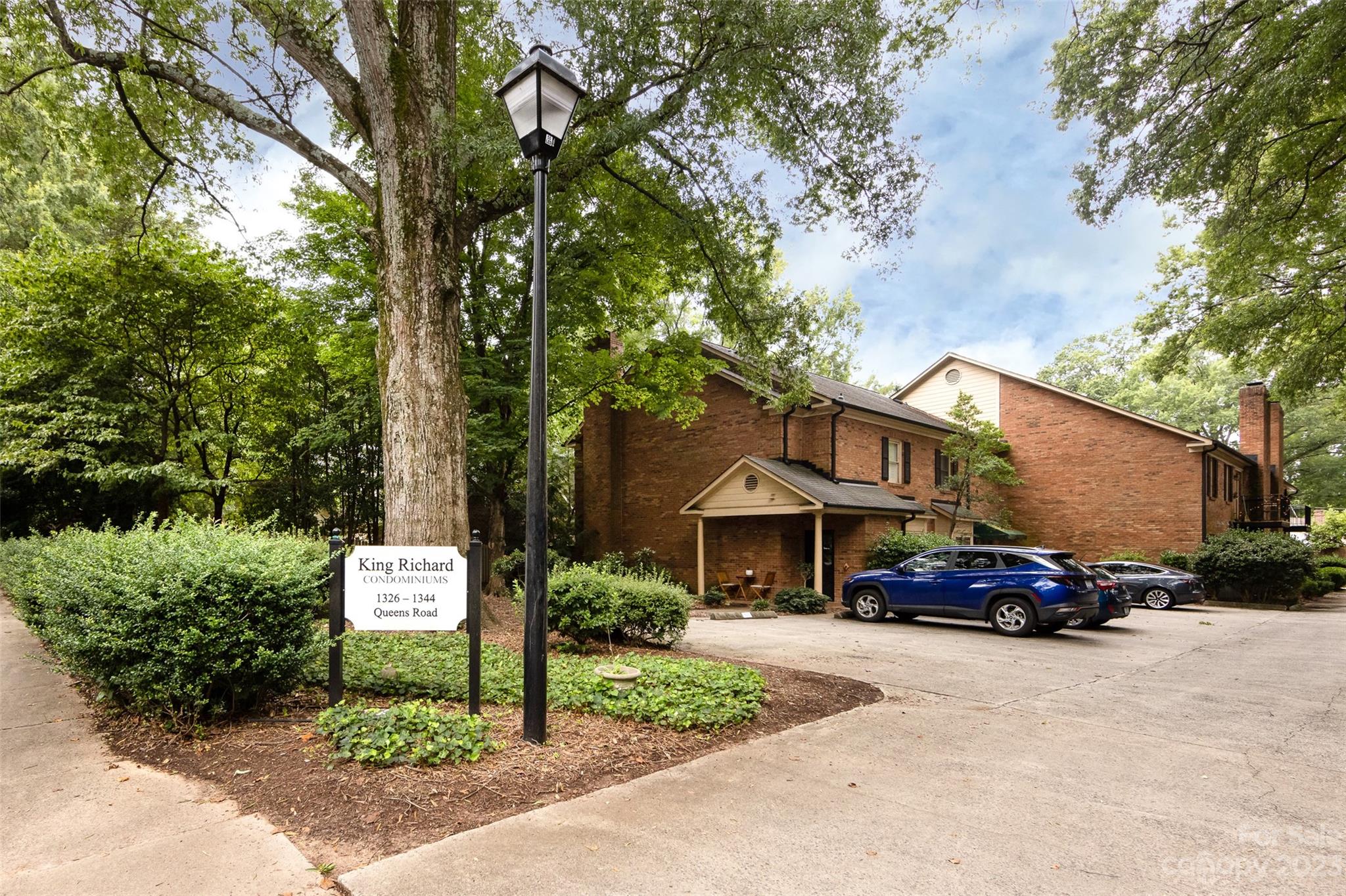 a car parked in front of a brick house with a large trees