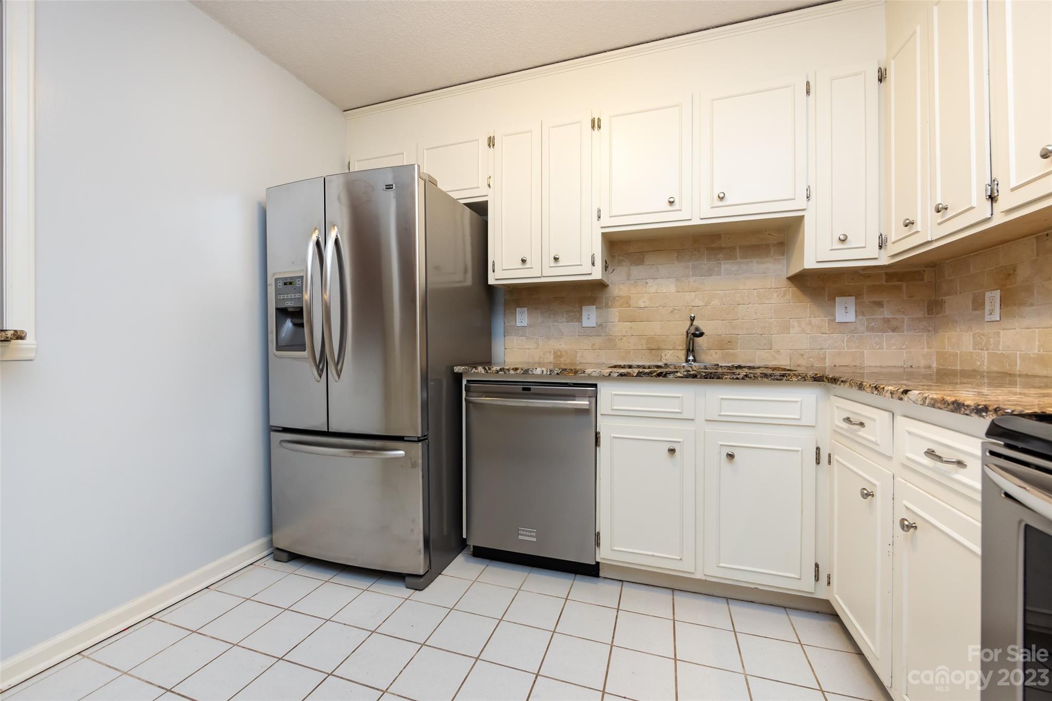 1336 Queens Road Charlotte, NC 28207 - Photo 19 of 36 a kitchen with white cabinets and refrigerator
