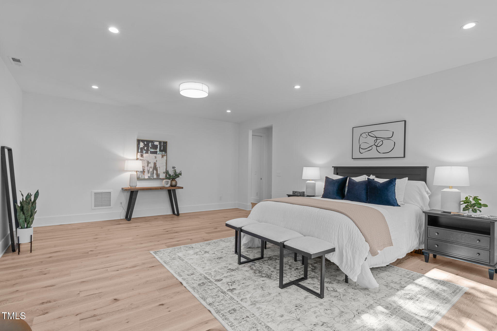 1406 Lyon Street, Unit 101 Raleigh, NC 27608 - Photo 27 of 62 a spacious bedroom with a bed a table and painting on the wall