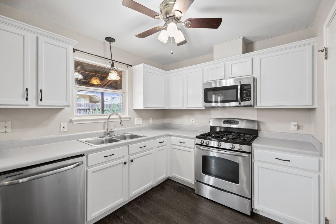 413 Clarks Way Hutto, TX 78634 - Photo 11 of 34 Kitchen with appliances with stainless steel finishes, hanging light fixtures, light countertops, dark wood-style flooring, and white cabinets
