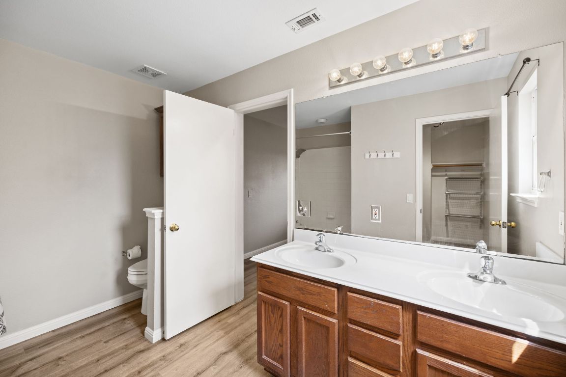413 Clarks Way Hutto, TX 78634 - Photo 16 of 34 Bathroom with double vanity, light wood-style flooring, and a walk in closet