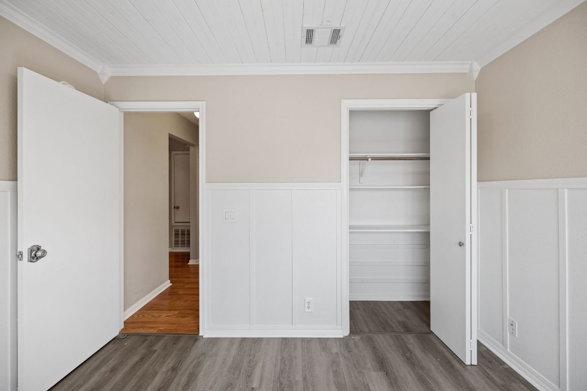 413 Clarks Way Hutto, TX 78634 - Photo 25 of 34 Unfurnished bedroom featuring crown molding, a wainscoted wall, a decorative wall, wood finished floors, and a closet